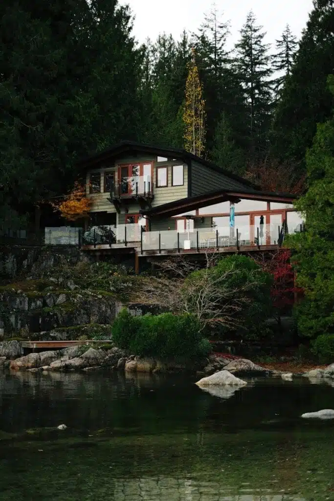 Modern house nestled in a lush forest by the water.