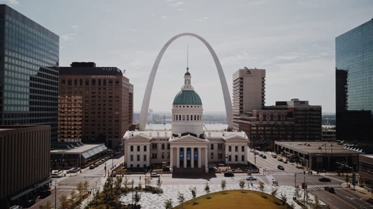 St. Louis real estate like this amazing white and green arch and dome in between high-rise buildings during daytime